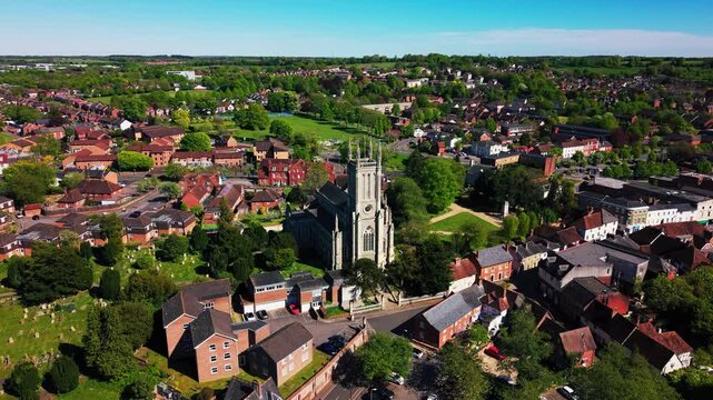 Wide aerial drone footage pulling back from St Mary&rsquo;s Church in Andover, revealing the historic church tower, churchyard, surrounding houses, rooftops, roads, green spaces, and wider Hampshire