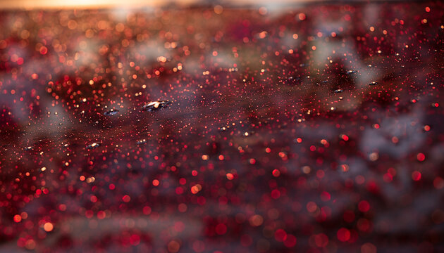 Glistening water droplets resting on a smooth surface reflecting intense ruby red and warm orange lights, captured with a shallow depth of field to emphasize rich textures and cinematic rain mood.