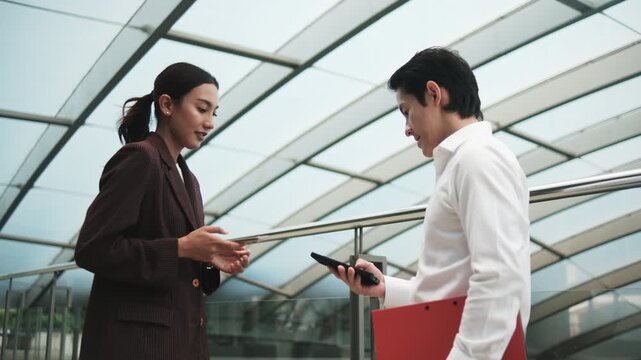 Young Asian smart businesspeople exchange digital contact information with NFC QR code, wireless mobile phone app technology, contactless startup collaboration at outdoor workplace, modern lifestyle.