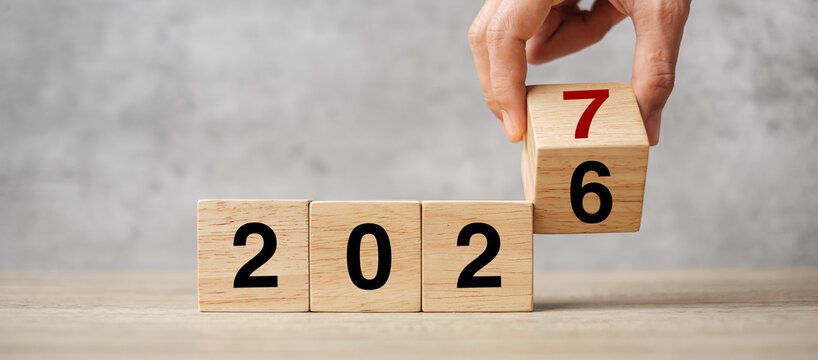 hand flipping block 2026 to 2027  text on table. Resolution, strategy, plan, goal, motivation, reboot, business and New Year holiday concepts