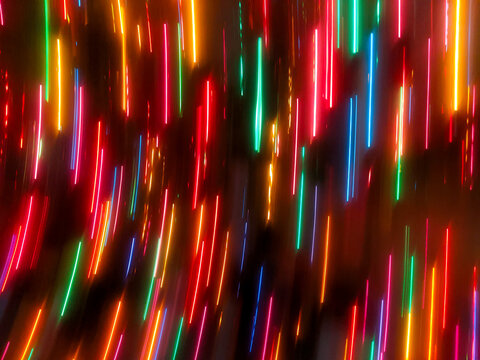 An abstract, full-frame intentional camera movement (ICM) shot showing vibrant red, orange, green, and blue holiday lights blurred into bright vertical streaks against a dark backdrop.