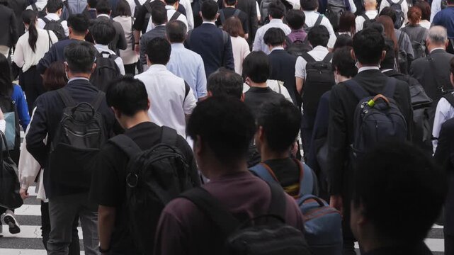 横断歩道を渡り朝の通勤するビジネスマンたちの後ろ姿のスローモーション　東京