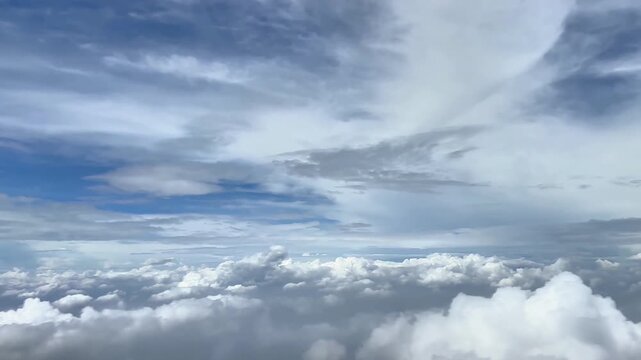 Clouded blue sky through aircraft window high altitude flying passing by