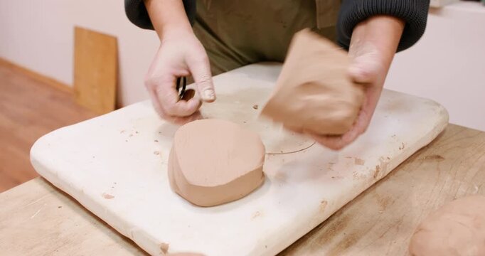 Clay shaping. Pottery workshop. Unrecognizable woman artisan creative hand cutting raw with thread using in ceramic artistic workplace.