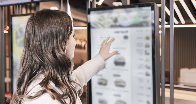 Woman interacting with digital touchscreen menu in restaurant, intuitive interface and modern technology interaction concept