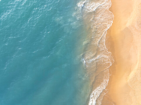 Natural coastal background showing ocean waves flowing across sandy beach from aerial perspective. Ideal visual for tourism marketing, holiday branding, and tropical lifestyle design.