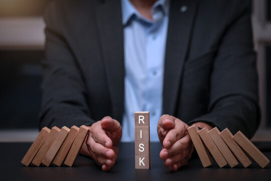 Focused businessman taking proactive action to stop falling dominoes for successful risk management protecting business assets and growth