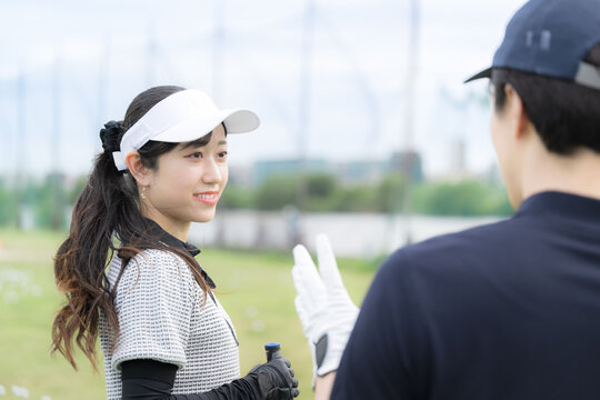 笑顔でゴルフを習う女性　ゴルフの先生と会話や2人でコミュニケーションをゴルフレッスンの様子