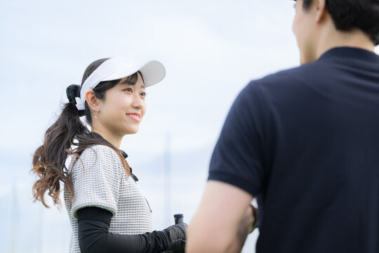 笑顔でゴルフを習う女性　ゴルフの先生と会話や2人でコミュニケーションをゴルフレッスンの様子