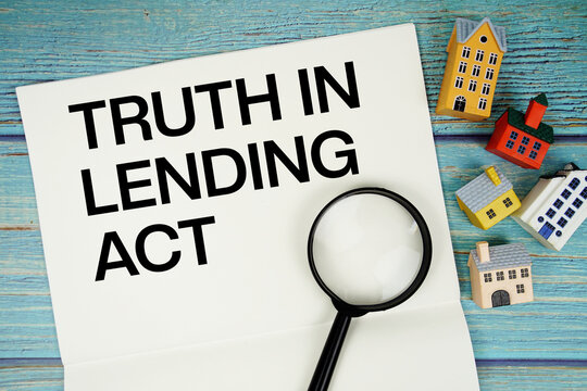 Notepad with "TILA Truth In Lending Act" with magnifying glass and house model on wooden background