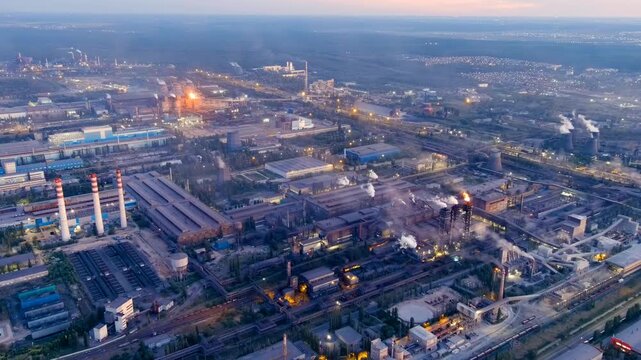 Lipetsk, Russia. Novolipetsk Metallurgical Plant, iron and steel works with blast furnaces and smokestacks, Drone footage at twilight with industrial torch flames glowing against the evening sky. Dro