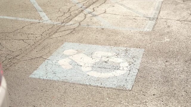 Faded Worn Wheelchair Accessibility Symbol on Old Pavement