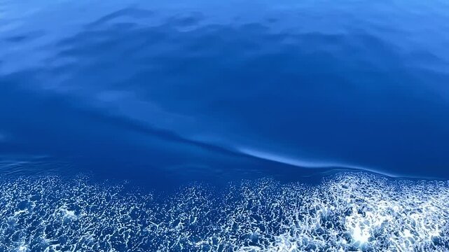 Slow motion view of a boat wake on blue tropical water near Coron Palawan Philippines with white sea foam smooth wave boundary and open ocean texture