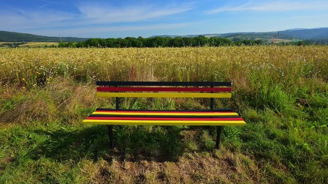 Sitzbank in den Farben der deutschen Flagge vor einem Blumenfeld mit Schlafmohn (Papaver somniferum), und Klatschmohn (Papaver rhoeas), Sommer, Germerode, Geo Naturpark Frau-Holle-Land, Hoher Meissner