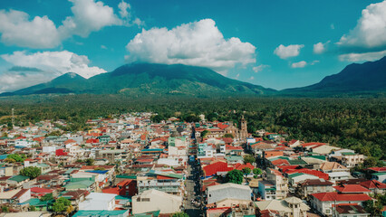 Horizontal Aerial Shot of Liliw Laguna Under Blue Sky, Scenic Townscape with Mount Banahaw Peaks and Red Rooftops, Rural Philippines Province Landscape © Gids Stories
