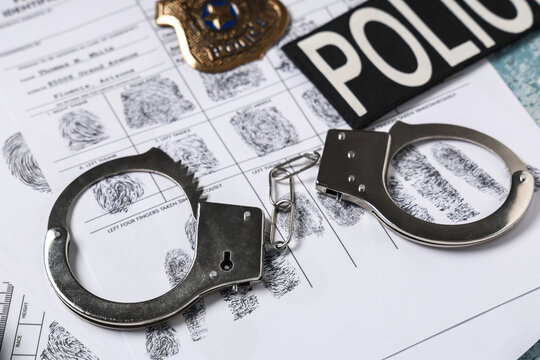 Handcuffs, fingerprints sheets, word POLICE and shield, closeup