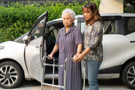 Caregiver help Asian elderly woman disability patient get in her car.