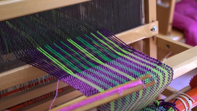 Child weaving colorful fabric on traditional wooden loom in slow motion