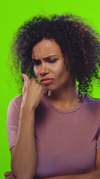 Annoyed African American woman expressing rude and dissatisfied emotions in green screen studio. Angry talking performance with demanding attitude, frustration and judgmental facial expressions.