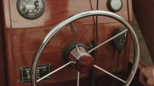 Chrome steering wheel and RPM tachometer on a polished wooden boat cockpit panel