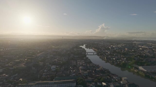 Drone footage moving left above Pasig River and Metro Manila during sunrise with glowing skies and expansive urban scenery.