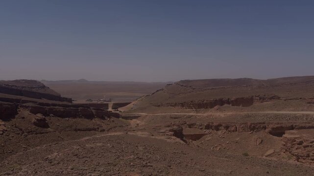 Expansive rocky canyon terrain with eroded plateaus and distant hazy mountains in Morocco