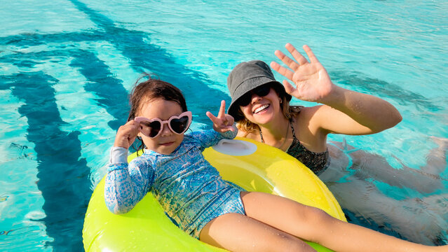 Mother and daughter having fun in swimming pool with inflatable ring - Family summer vacation