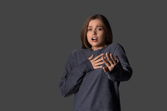 Young woman having panic attack on dark background