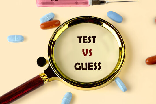 Pills and a syringe rest on a pale surface next to a magnifying glass, which clearly displays the words TEST VS GUESS, symbolizing accuracy in medical decisions