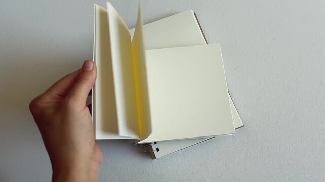 Hand Flipping Through Blank Sketchbook Pages on White Background