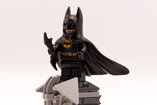 Bologna - Italy - April 2026: Batman lego minifigure standing on a grey brick pedestal holding a batarang weapon against a plain white background.