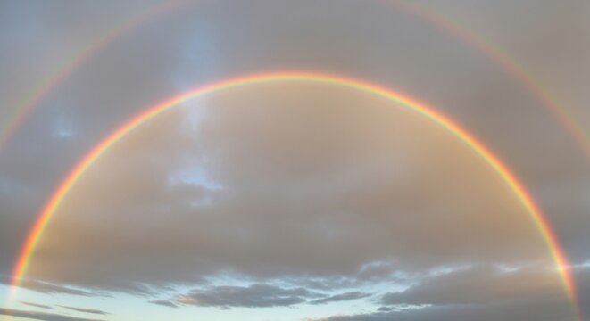 Double Rainbow Arching Through Clouds: A stunning double rainbow creates a vibrant arc across a cloudy sky, a breathtaking natural phenomenon signifying hope and wonder.