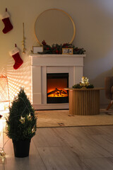 Fototapeta premium Fireplace with Christmas decorations and glowing lamp in dark living room