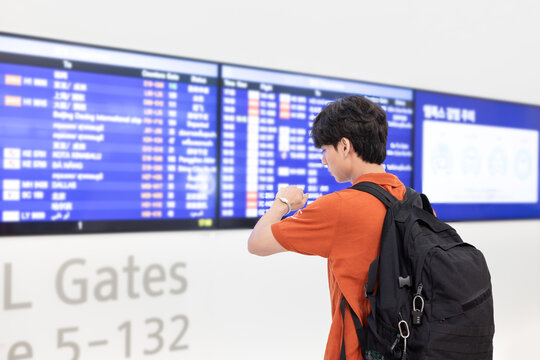 Korean Backpacker Reading Flight Information Display Board at Incheon Airport