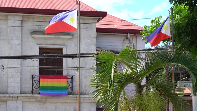 Philippine flags waving alongside LGBT pride flag on a historic building