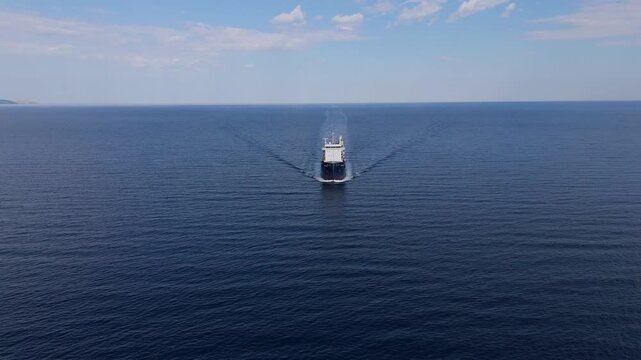 Detailed aerial perspective of a cargo ship front cutting through the ocean water, creating a white foam.