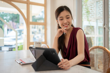 Fototapeta premium Young Woman Enjoying Coffee While Using Tablet in Coffee Shop