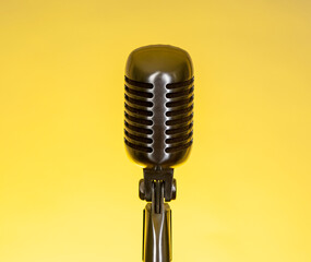 Fototapeta premium Vintage microphone stands alone against a bright yellow background for music recording or performance setting