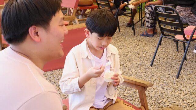 Father and son enjoying ice cream at outdoor cafe