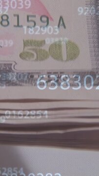 Vertical video: On scan, camera panning over stacked 50s, numbers floating to reveal serials