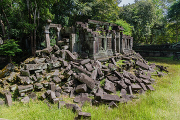 Fototapeta premium The ancient ruins of Beng Mealea temple in Cambodia, near Siem Reap, lie in disarray, with large stone blocks scattered across the overgrown grounds, showcasing the passage of time