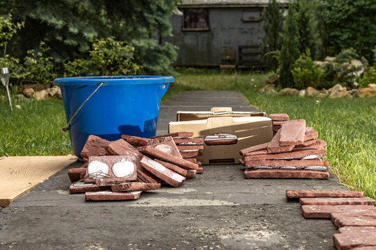 Building materials, bricks, mortar and tools for plastering and tiling placed on the sidewalk in front of the house,