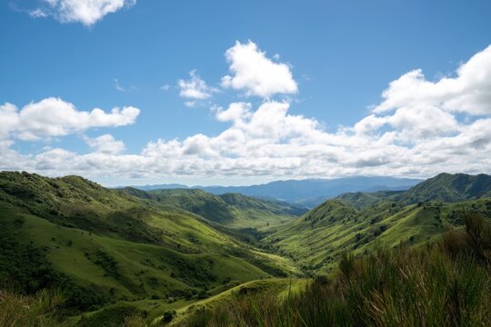 The valley of rolling green hills under a bright blue sky with clouds