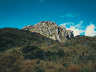 Fototapeta premium Rocky Andean mountain peak with highland páramo vegetation under blue sky in Ecuador