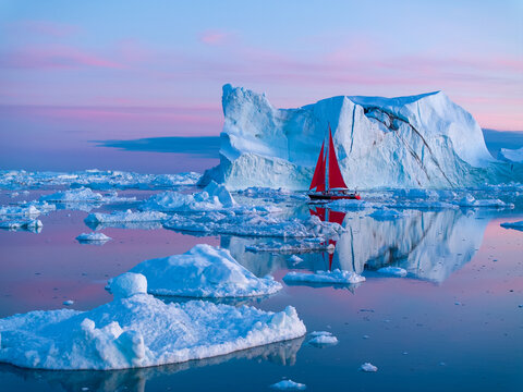 Segelboote mit roten Segeln zwischen Eisbergen in Ilulissat in Gr&ouml;nland in der wundersch&ouml;nen, bunten und romantischen Mitternachtssonne
 
