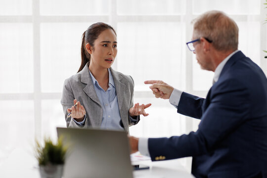 Businesswoman experiencing workplace bullying, stress, and emotional distress from an aggressive male manager's verbal abuse and toxic behavior during a corporate conflict discussion