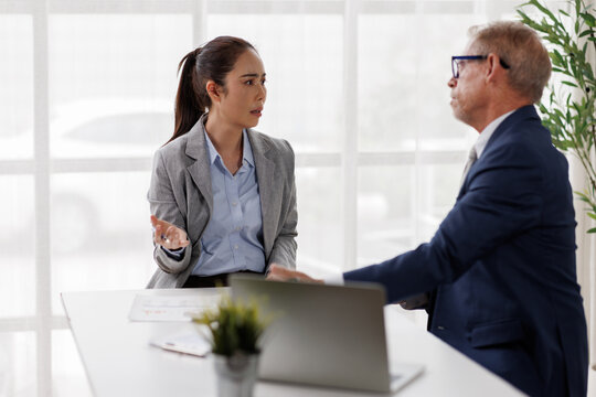 Businesswoman in a tense office meeting gesturing with an open hand while speaking to a male colleague, conveying disagreement, misunderstanding, and workplace conflict during discussion