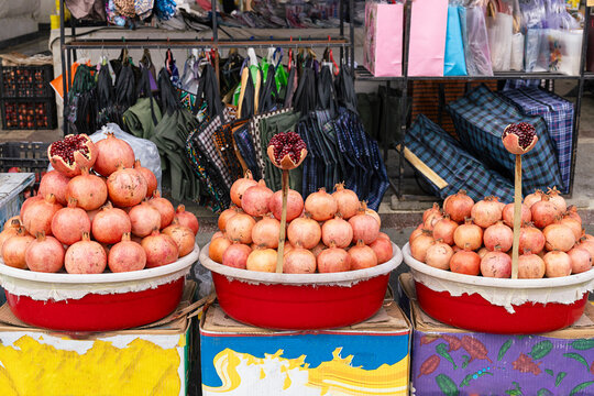 Pomegranates stacked in pyramids at Siab Bazaar in Samarkand with cut fruits showing red seeds. Ideal for travel, food, and cultural content about Central Asian markets.**KEYWORDS:** pomegrana...