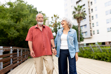 Naklejka premium Happy senior couple walking hand in hand in park