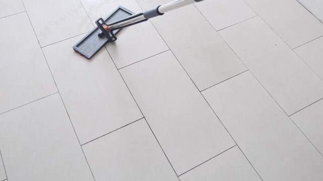 Close Up of a Flat Mop Cleaning and Washing Tiled Floor in a Room